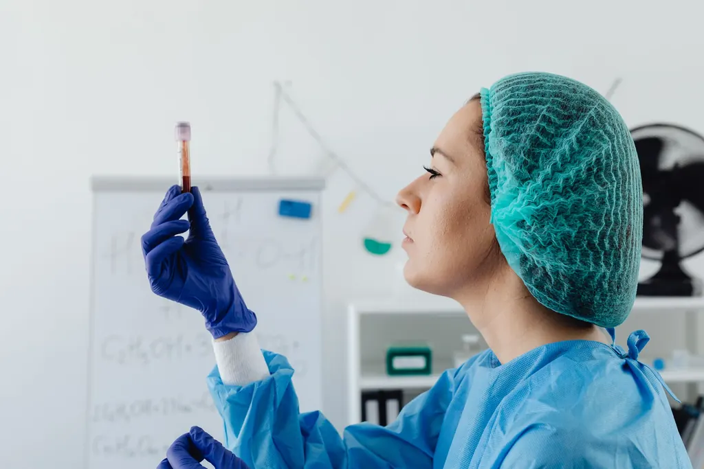 Técnica de laboratório de touca e luvas conferindo um tubo de coleta de sangue